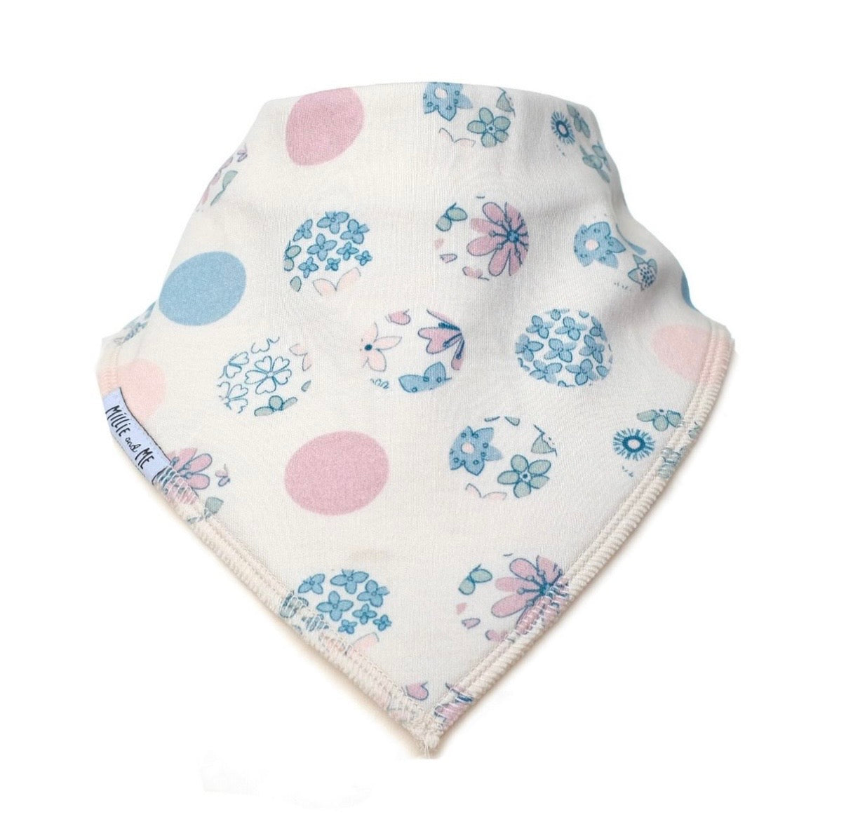 A triangular baby bandana bib in off-white cotton, featuring a pattern of light blue and pink polka dots, flowers, and butterflies. The brand name 'Millie and Me' is printed on the side edge.