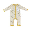 A baby long-sleeve footless one-piece sleeper in cream with a small yellow and blue floral print, featuring mustard yellow trim and a white hangtag.