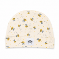 A cream-colored baby beanie hat featuring a playful pattern of yellow and black bumblebees, small yellow dots, and dotted whimsical lines. The hat has a folded cuff with a white square patch displaying the black stylized 'MM' logo.