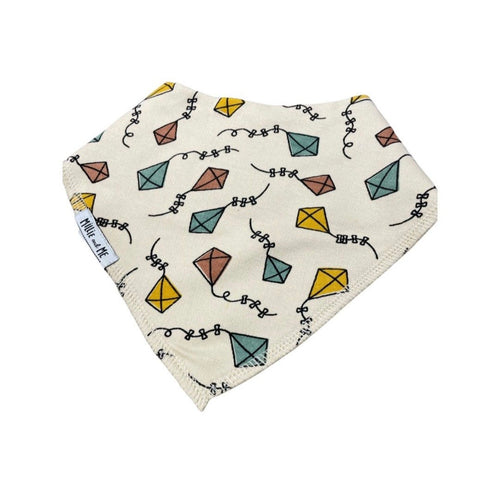 An off-white cotton bandana bib featuring a colorful pattern of paper kites and black squiggle lines, with a white fabric label on the side.