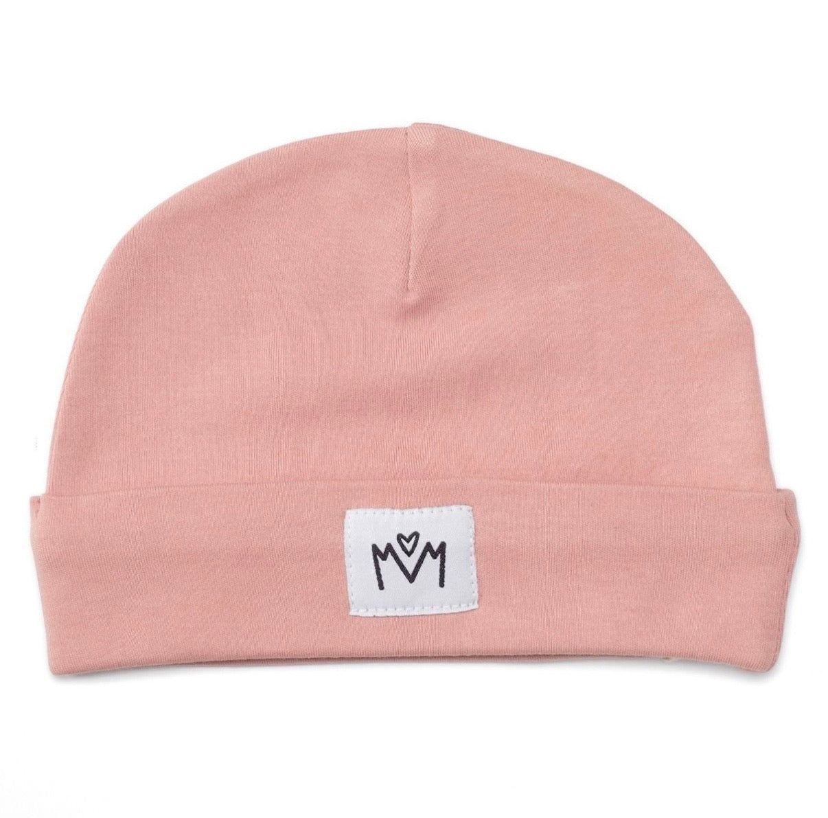 A dusty pink knit beanie hat with a folded cuff, featuring a small white square patch on the front with a black embroidered logo.