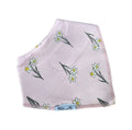 A light pink baby bib with a daffodil pattern, featuring white flowers with yellow centres and green stems. The bib has a small white label at the bottom that reads 'Millie and Me'.