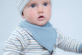 A close-up of a baby wearing a light blue triangular bib.
