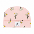 A light pink knit beanie hat featuring a repeating pattern of white daffodils with yellow centers and dark stems, with a white rectangular patch on the front displaying a black stylized 'MM' logo.