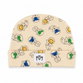 A beige baby beanie hat featuring a playful pattern of cartoon astronauts and planets in blue, green, and yellow. The hat has a folded cuff with a white square patch displaying the black 'MM' logo.