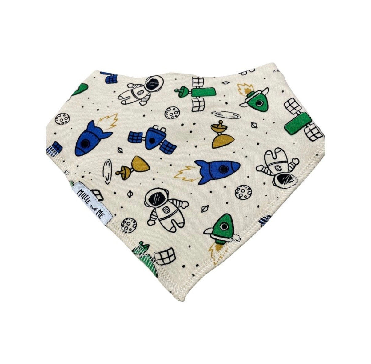A triangular bandana bib with an off-white background printed with a colourful space-themed pattern of astronauts, rockets, satellites, and planets. The brand name 'Millie and Me' is visible on a small fabric tag on the left side.