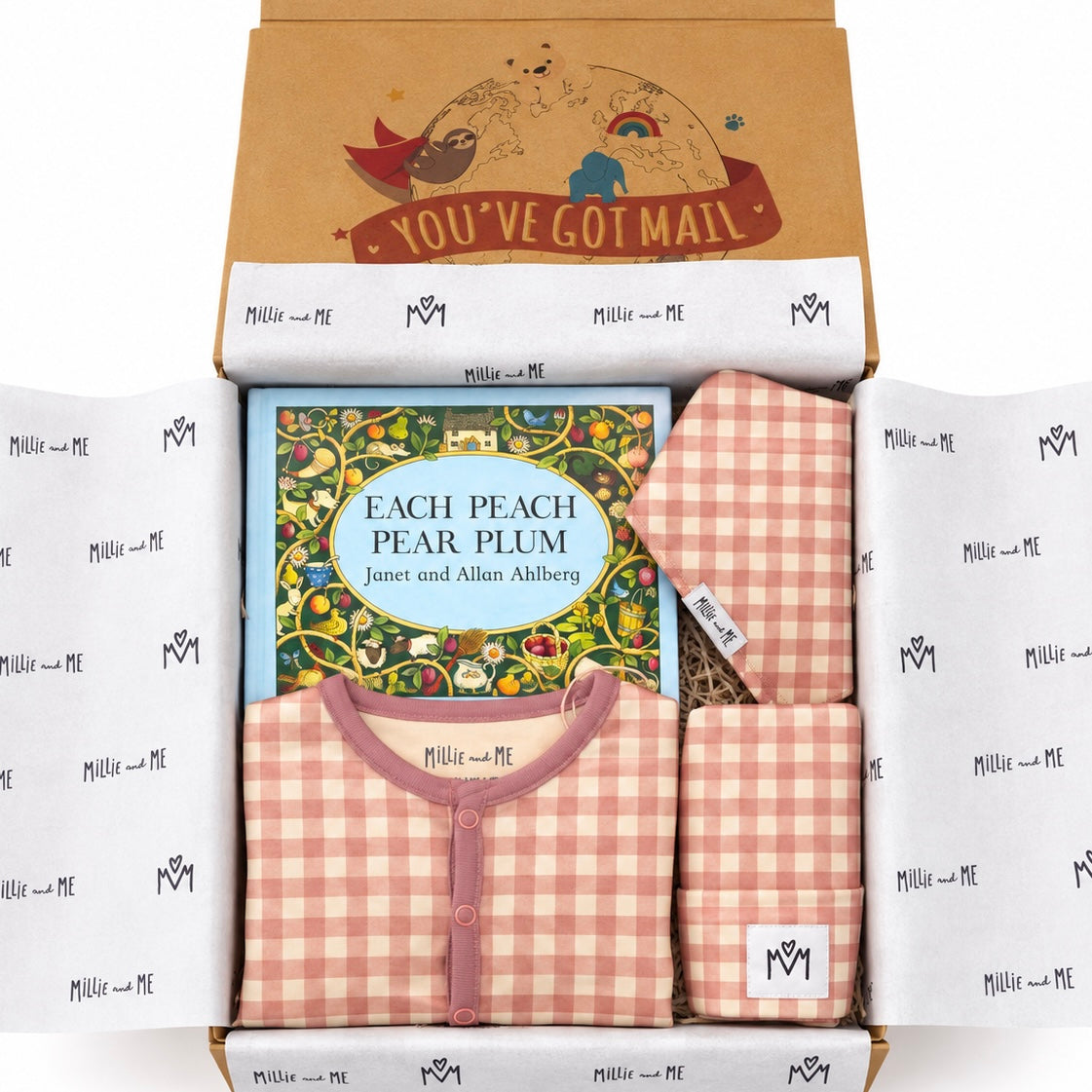 A curated gift box from Millie and Me featuring a children's outfit set, a book, and a letter. The set includes a pink and white gingham romper, matching hat, and a matching bib, arranged inside a cardboard box with a printed letter insert and branded tissue paper.