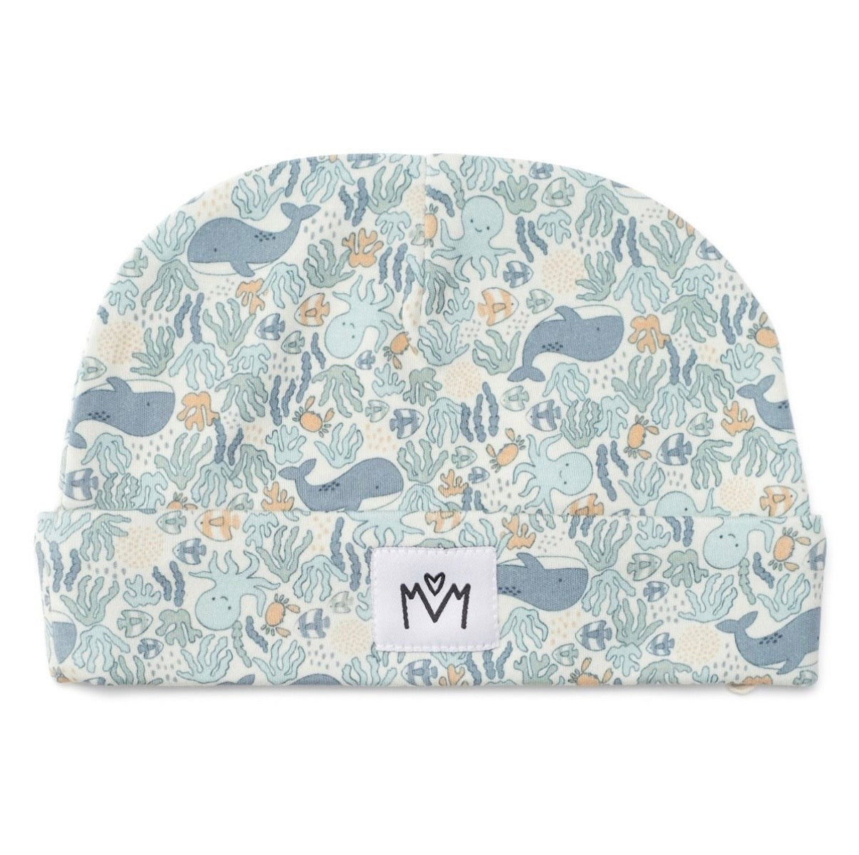 A baby beanie hat featuring a playful underwater pattern with whales, octopus, sea plants, and small fish in muted blue, gray, and beige tones. A small white fabric brand patch with a black logo is sewn onto the front cuff.