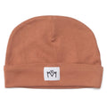 A russet beanie hat with a folded cuff and a small white square patch featuring a black embroidered logo, shown against a plain white background.