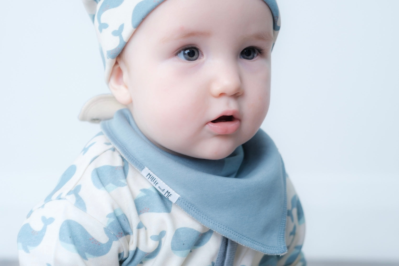 A close-up of a baby wearing a light blue triangular bib.