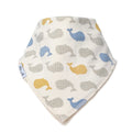 A triangular baby bandana bib with an off-white background, featuring a pattern of stylised whales in blue, grey, and mustard yellow. A small white fabric tag on the left edge displays the brand name 'Millie and Me'.