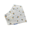 A folded white baby bib with a cute pattern of yellow and black bees, blue flowers, and small yellow dots. The brand name 'Millie and Me' is visible on a small blue tag at the bottom edge.