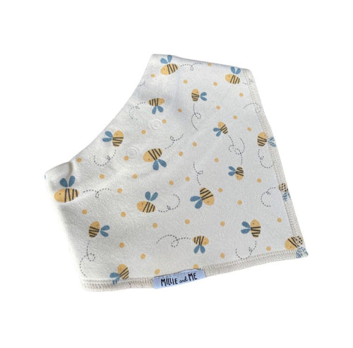 A folded white baby bib with a cute pattern of yellow and black bees, blue flowers, and small yellow dots. The brand name 'Millie and Me' is visible on a small blue tag at the bottom edge.