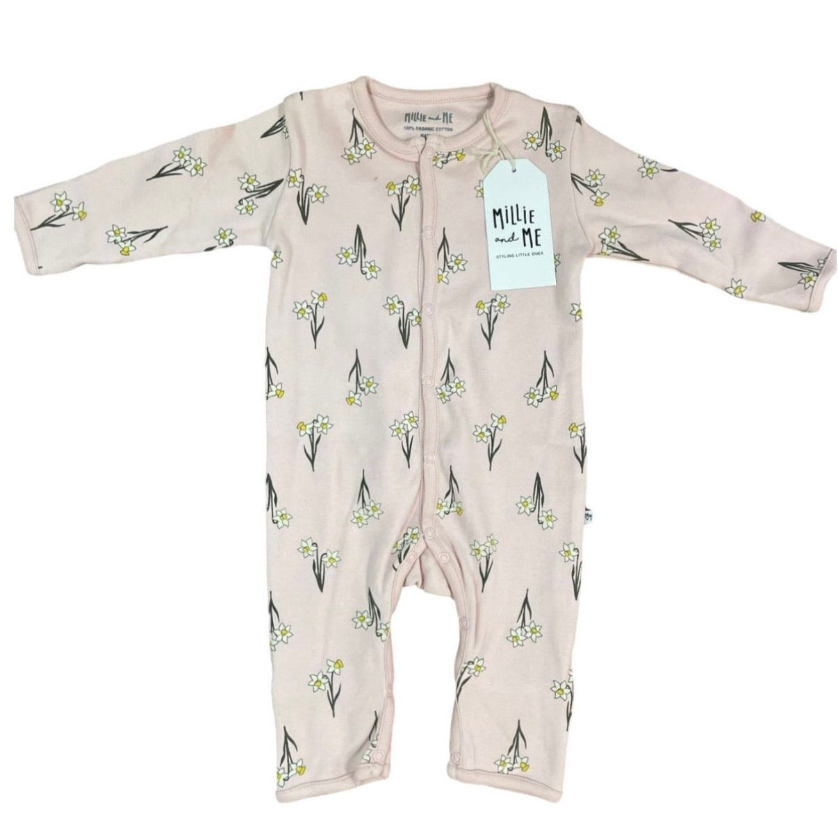 A baby long-sleeve footless one-piece romper in a pale blush pink, featuring an all-over print of small white flowers with green stems. The garment is laid flat on a white background and has a white paper brand tag that reads 'Millie and Me'.