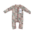 A baby long-sleeve footless one-piece sleeper with a dense floral and geometric pattern in muted pink, green, and brown on a cream background, featuring a white hangtag with the brand name 'Millie and Me'.