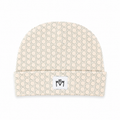 A beige beanie with a repeating light gray hexagonal pattern and a white rectangular patch on the folded cuff featuring a black stylized 'MM' logo.