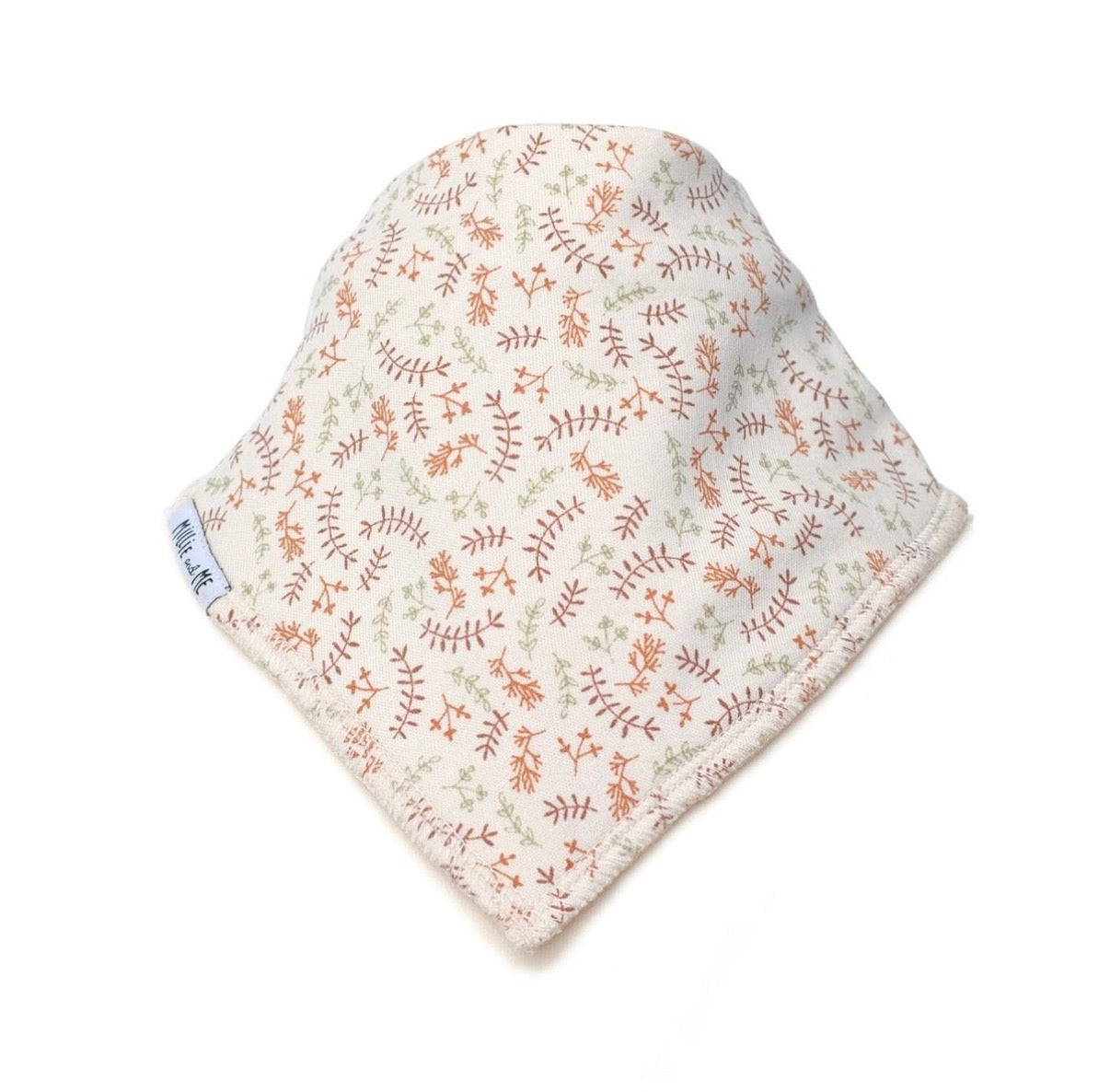 A soft baby bonnet or hat made of cream-colored fabric with a delicate all-over botanical pattern in muted terracotta and sage green, featuring a small white fabric brand tag on the side.