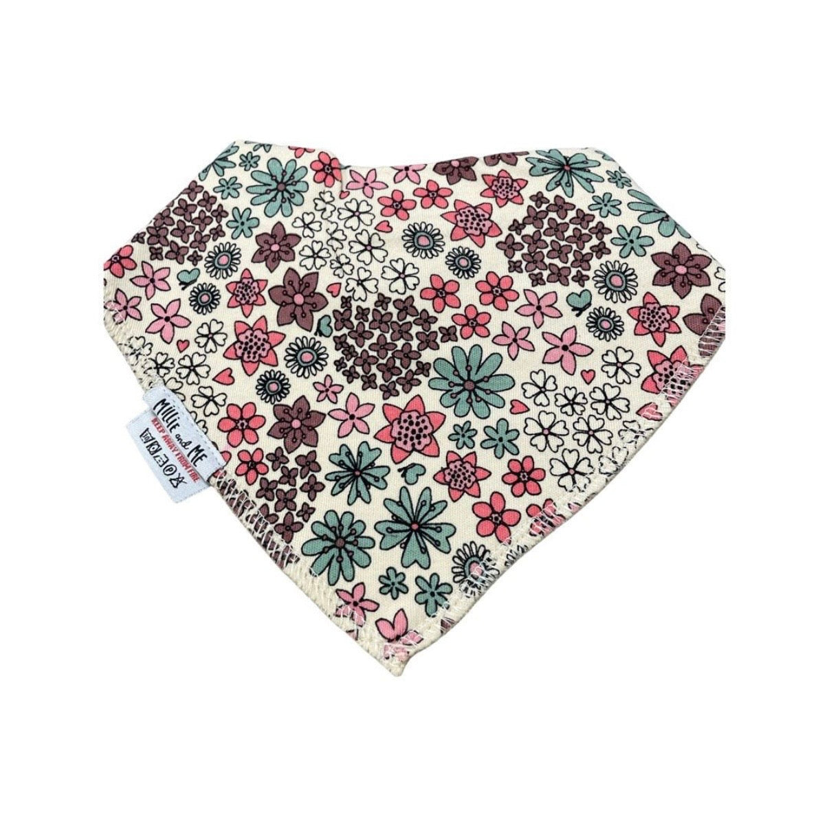 A triangular bandana bib with a dense floral pattern in pink, green, and dark brown on a cream background, featuring a white fabric tag with black text.