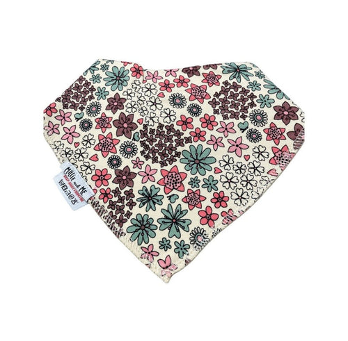 A triangular bandana bib with a dense floral pattern in pink, green, and dark brown on a cream background, featuring a white fabric tag with black text.