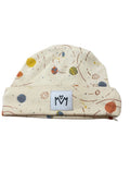 A cream-colored baby beanie hat featuring a colorful space-themed print with planets, stars, and orbit lines, complete with a white brand patch on the front.