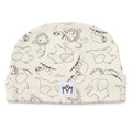 An off-white baby beanie with a black line art pattern of whimsical animals, featuring a small white brand patch with the letters 'MM' on the cuff.