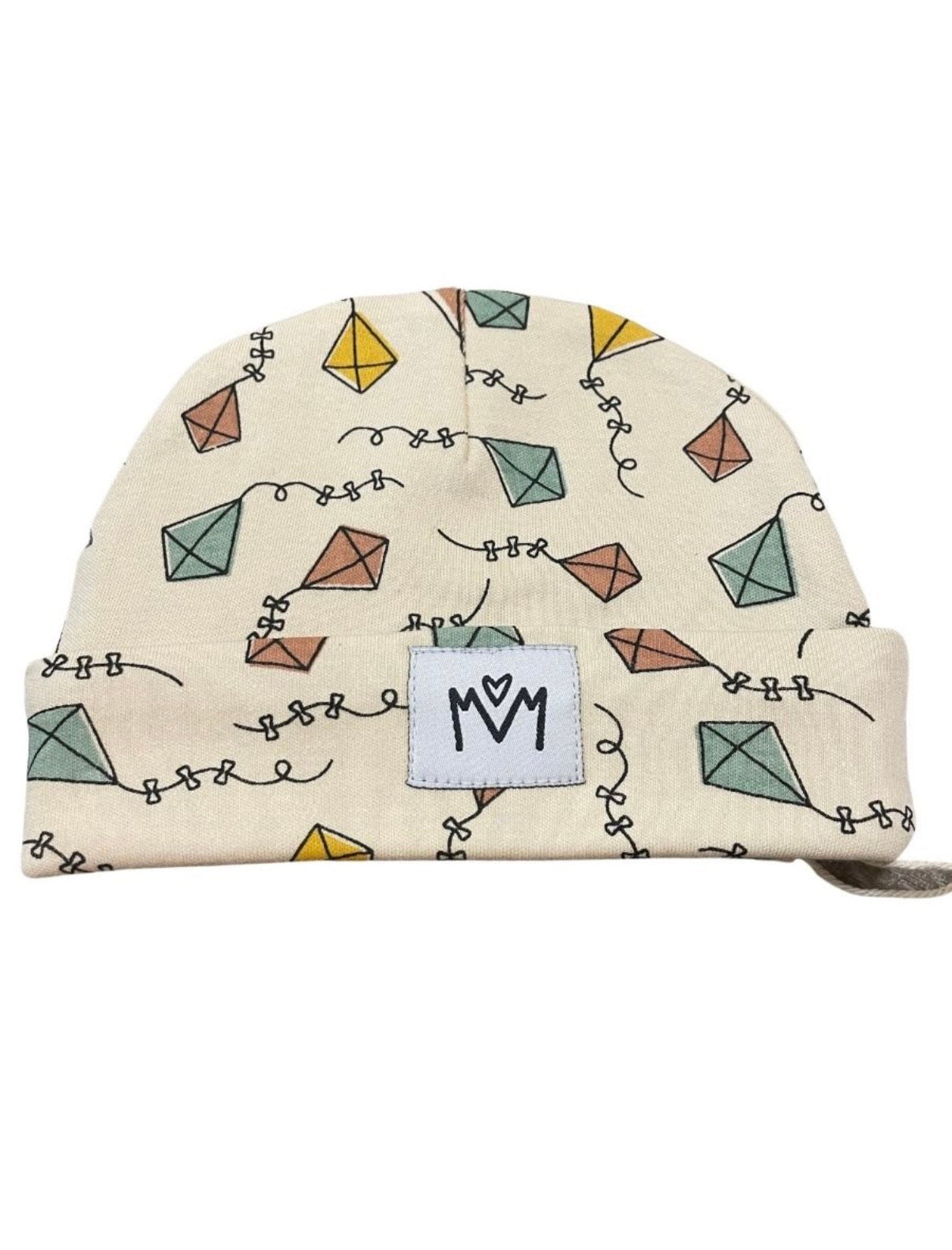 A cream-colored knit beanie hat featuring a pattern of colorful hand-drawn kites and black squiggle lines, with a white rectangular patch on the front folded cuff displaying the black logo.