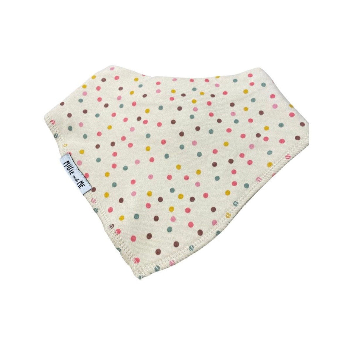 A triangular baby bib made of cream-colored fabric with a colorful polka dot pattern, featuring a small white tag on the side.