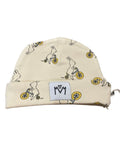 A cream-colored knit beanie hat featuring a repeating pattern of bunnies riding bicycles, with a white square patch on the cuff displaying the black logo.