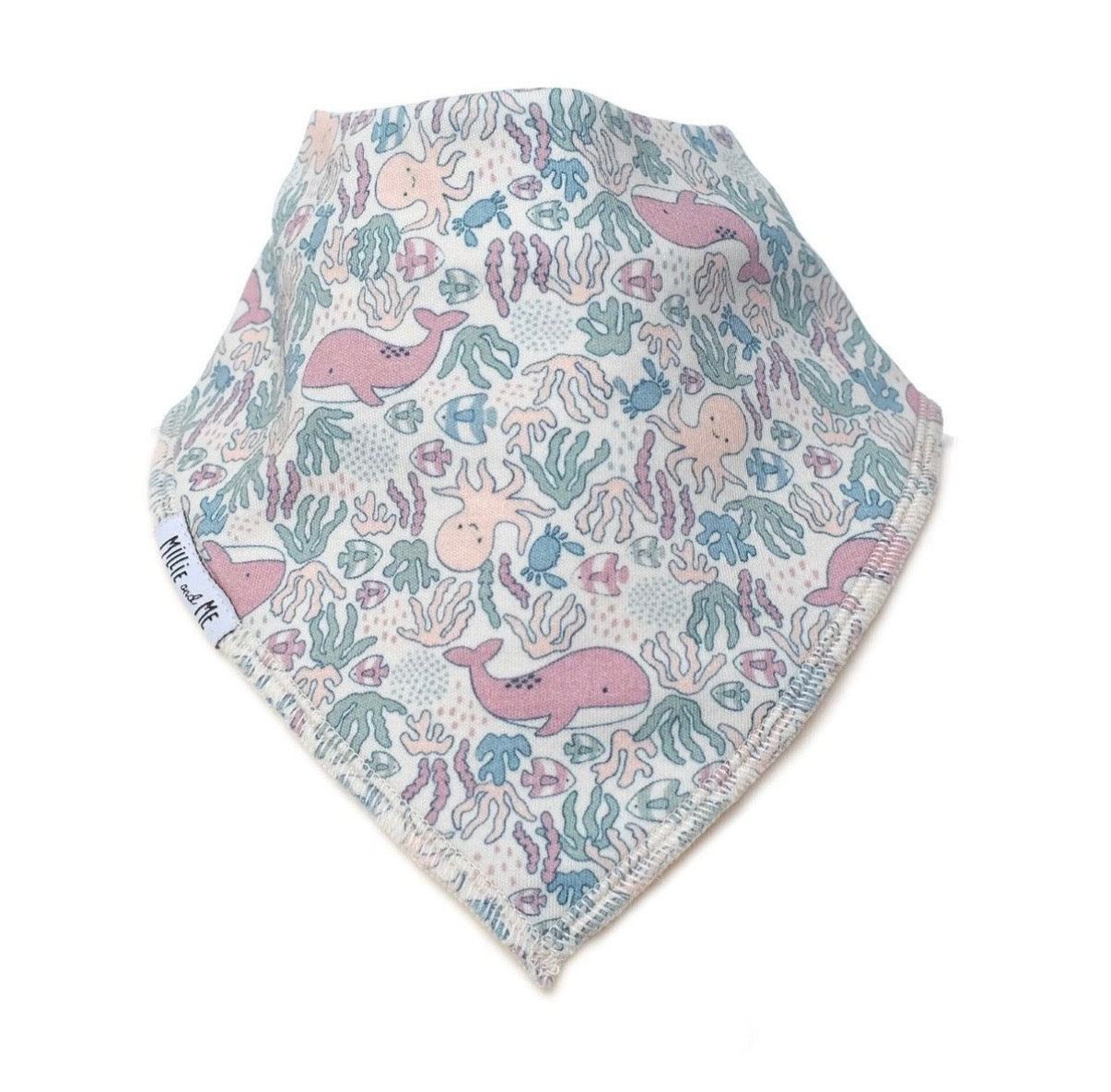 A triangular baby bandana bib with a pastel underwater print featuring pink whales, blue octopus, and green seaweed on a white background, with a visible 'Millie and Me' brand tag on the side.