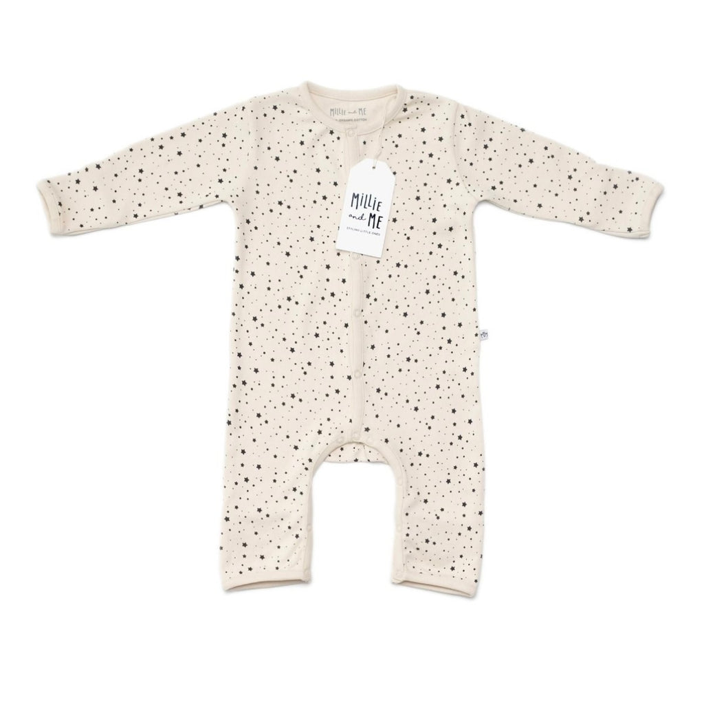 A long-sleeve baby romper in cream with a black speckled pattern, featuring a white hangtag with the brand name 'Millie and Me' and snap closures down the front.