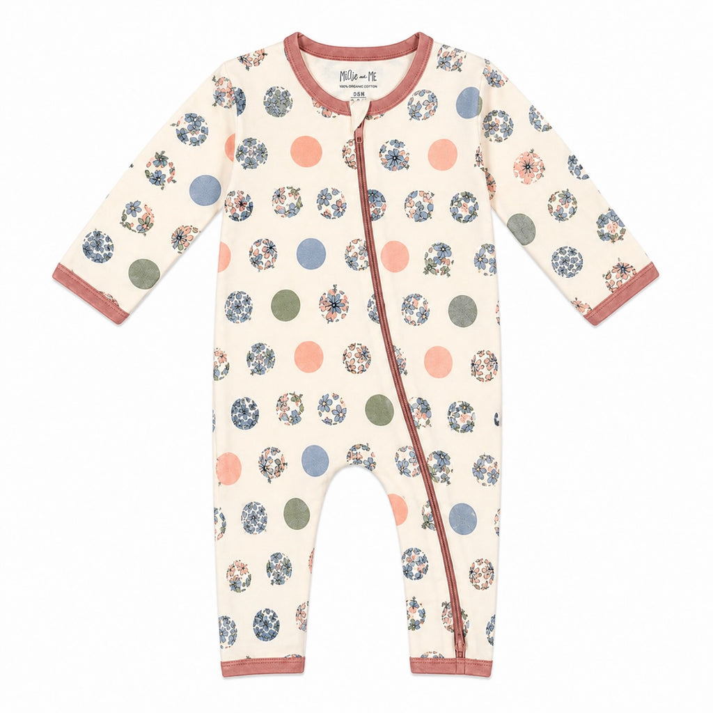 A long-sleeve baby footless one-piece sleeper with an off-white base, decorated with a pattern of polka dots and floral circles in muted blue, pink, green, and brown tones. It features a dusty rose trim along the collar, zipper placket, cuffs, and ankles.