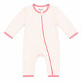 A baby long-sleeve footless sleeper in a white and pink geometric pattern, featuring pink trim on the collar, zipper, cuffs, and hem.