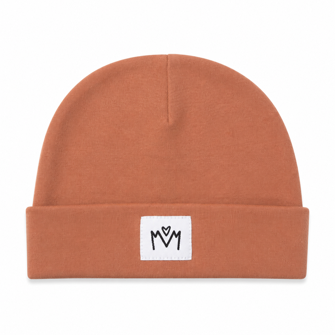 A terracotta orange knit beanie hat with a folded cuff, featuring a small white square patch on the front with a black embroidered 'M' logo.
