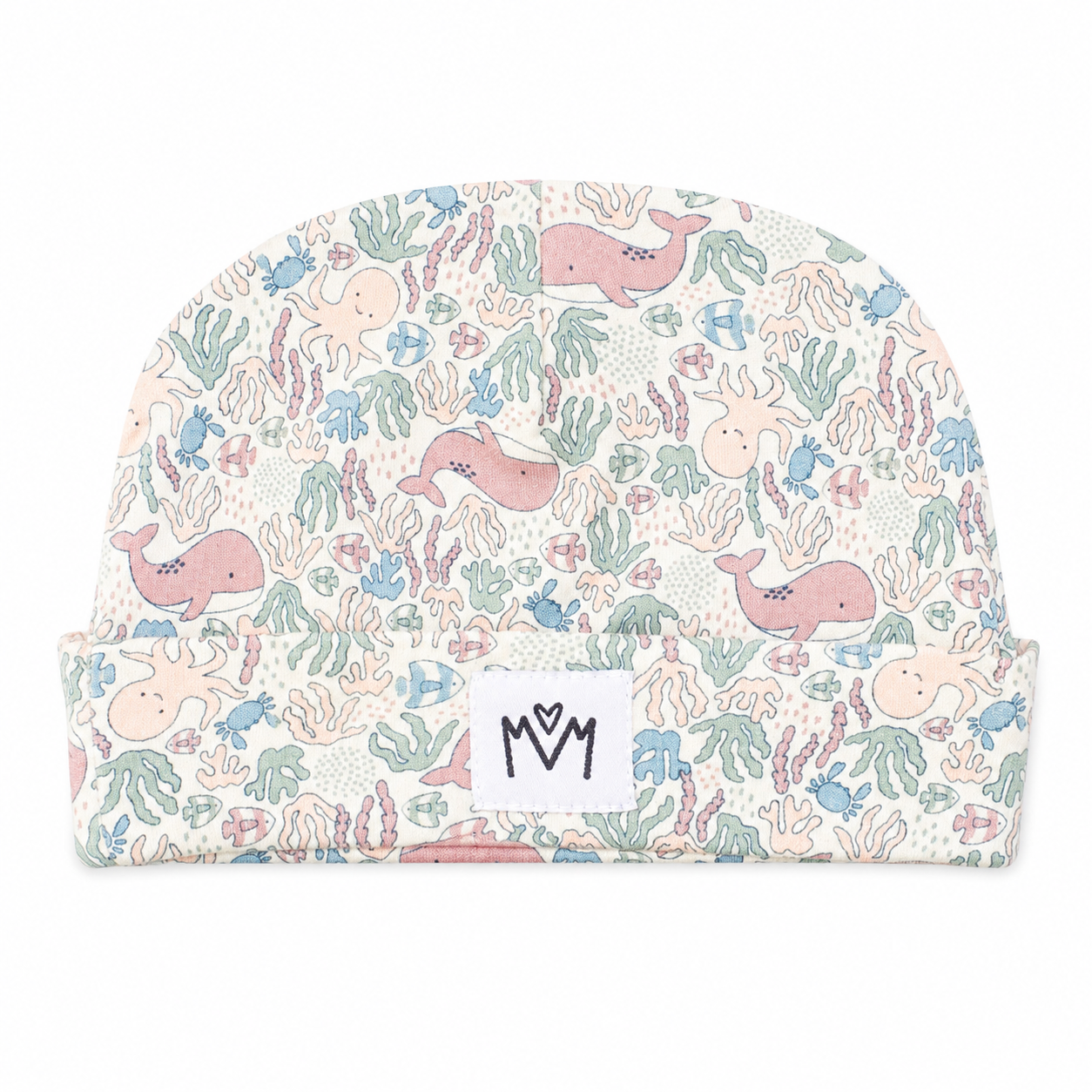 A baby beanie hat featuring a pastel underwater print with pink whales, blue octopus, and green coral on a cream background, with a white brand patch reading 'M M' on the front cuff.
