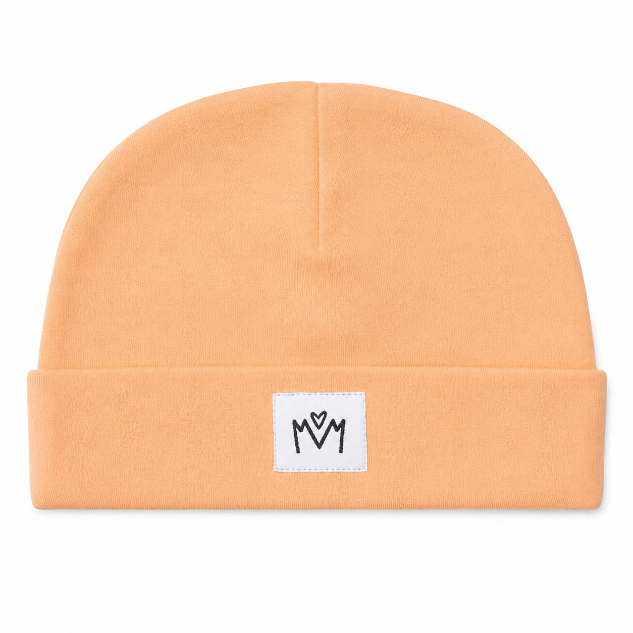A peach-colored knit beanie hat with a folded cuff, featuring a small white square patch on the front with a black embroidered 'M' logo.