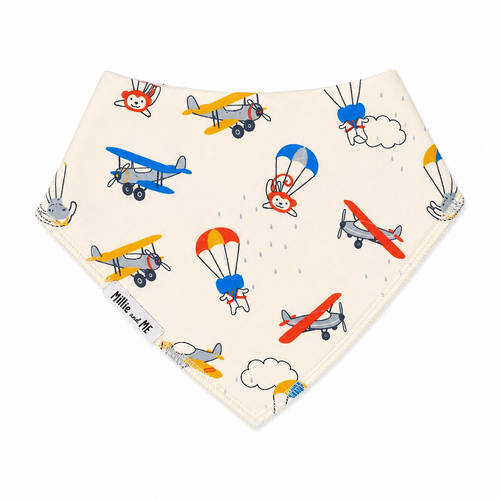 A triangular baby bandana bib in cream with a colourful pattern of vintage airplanes and hot air balloons, featuring the 'Mille and Me' brand label.