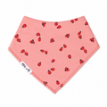 A pink triangular baby bandana bib with a red ladybug pattern, featuring a white 'Millie and Me' brand tag on the lower left edge, set against a plain white background.
