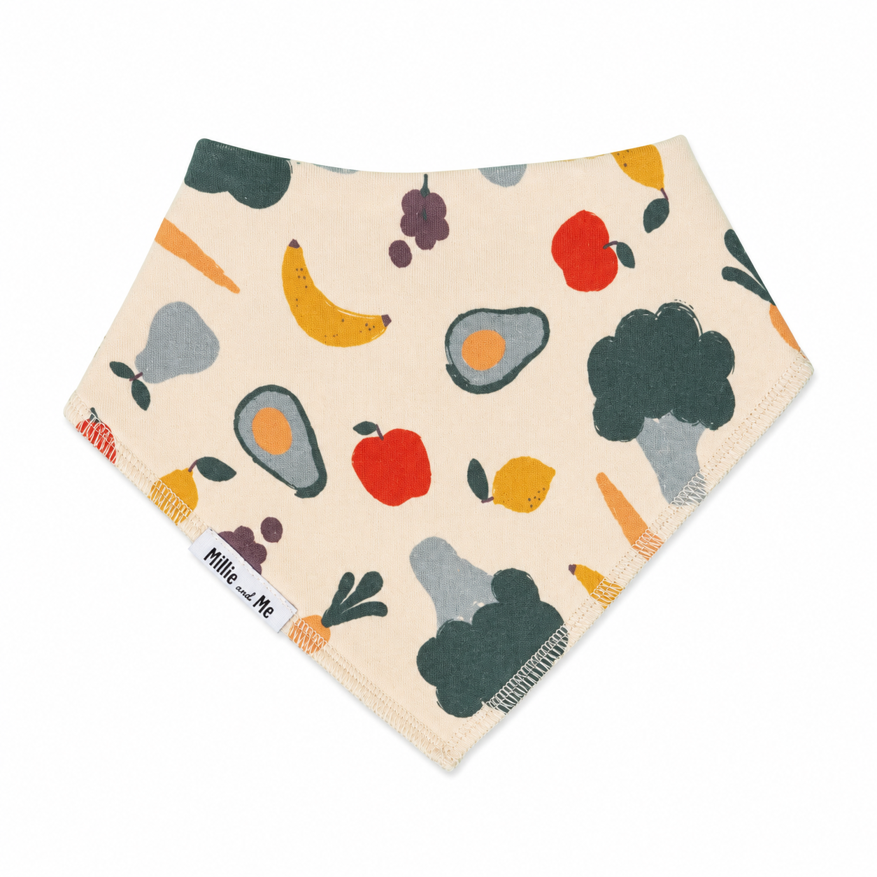 A triangular bandana bib with a cream background and a colorful print of fruits and vegetables, including avocado, banana, apple, carrot, and broccoli. A white fabric tag on the left side reads 'Millie and Me'.