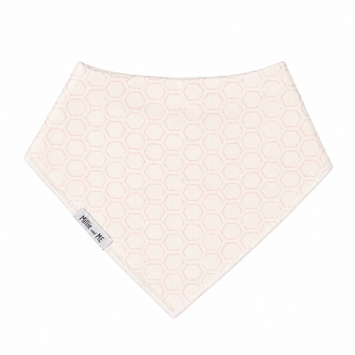 A triangular bandana bib in a warm cream color with a light pink hexagonal honeycomb pattern, featuring a small white brand tag that reads 'Millie and Me'.