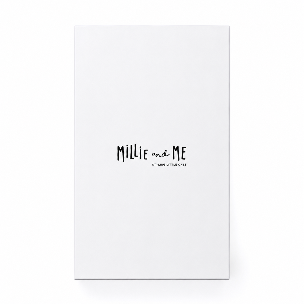 A tall, minimalist white gift box standing upright on a white background. The box features the text 'Millie and Me' in a black handwritten-style font, with 'STYLING LITTLE ONES' printed underneath in smaller text.