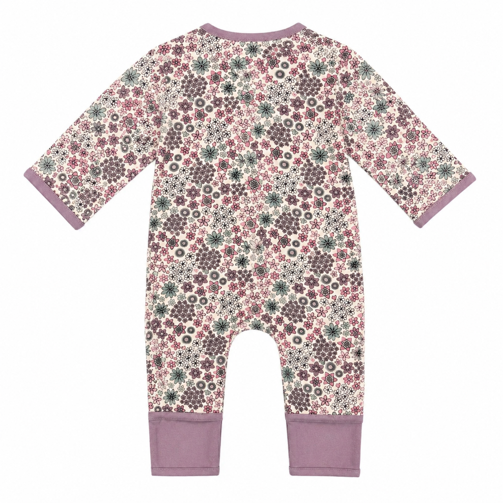 A baby long-sleeve footless one-piece jumpsuit with a dense floral and geometric pattern in dusty pink, mauve, olive green, and cream, finished with solid mauve trim on the collar, cuffs, and leg cuffs.