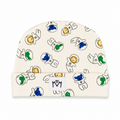 An off-white knit baby beanie featuring a playful pattern of cartoon astronauts in black outlines with blue, green, and gold accents. A small white fabric patch with a black 'MM' logo is sewn onto the folded cuff.