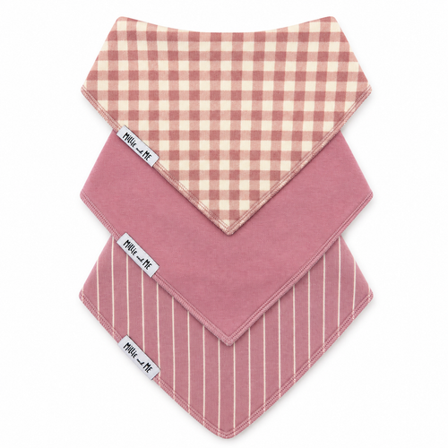 Three baby bandanas from Millie and Me stacked diagonally. The top bandana features a dusty pink and cream gingham check pattern, the middle is a solid dusty pink, and the bottom has a dusty pink background with thin cream vertical stripes.