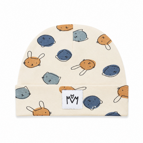 A cream-colored baby beanie hat featuring a playful pattern of cartoon animal faces in blue, gray, and orange. The hat has a folded cuff with a white fabric patch displaying the 'M M' logo.