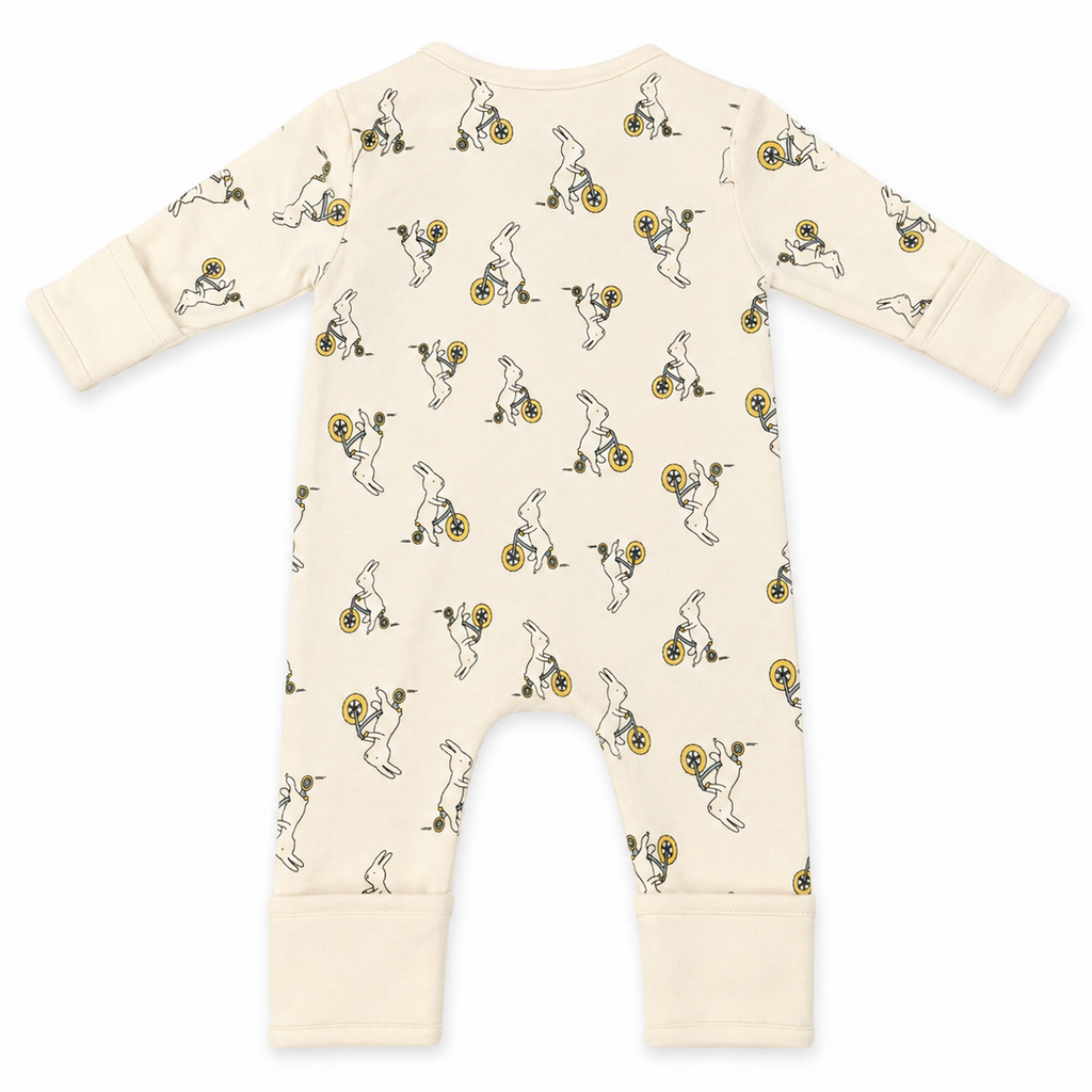 A cream-colored baby long-sleeve footless romper with an all-over print of cartoon rabbits riding yellow bicycles, shown flat on a white background.