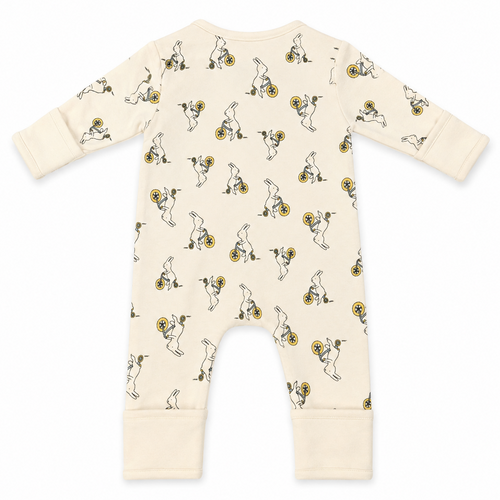 A cream-colored baby long-sleeve footless romper with an all-over print of cartoon rabbits riding yellow bicycles, shown flat on a white background.