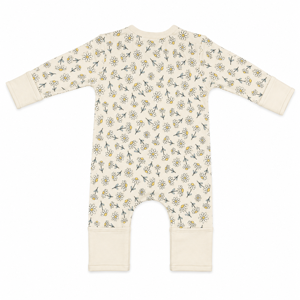 A long-sleeve baby romper in cream with a repeating daisy and wildflower pattern, featuring solid cream cuffs and leg openings.
