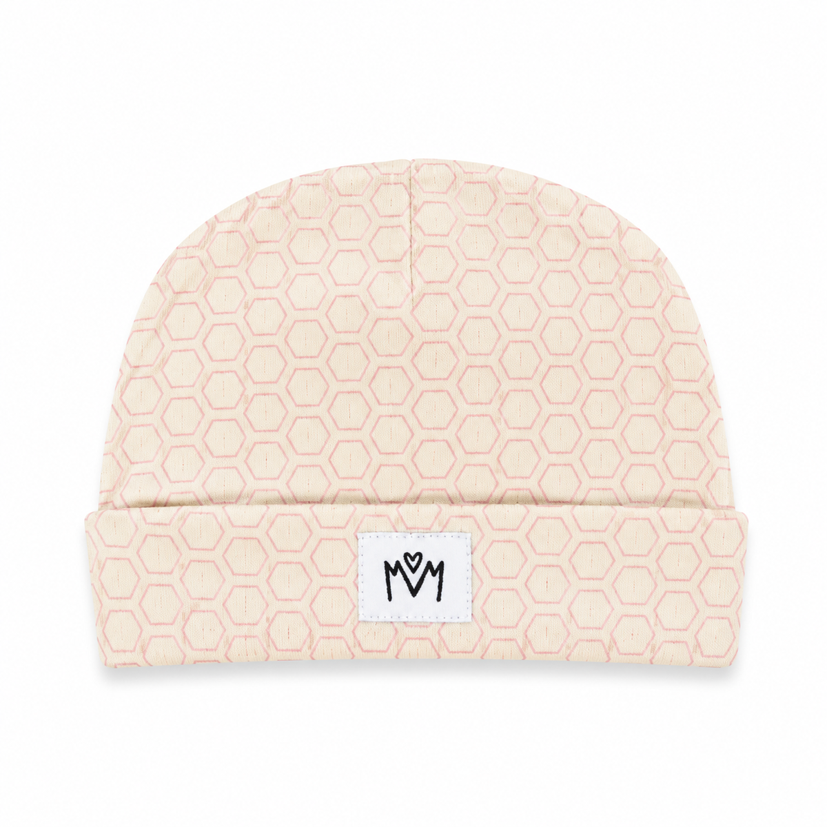 A light beige knit beanie with a repeating hexagon pattern in a soft pink, featuring a white rectangular patch on the folded cuff with a black stylized logo.