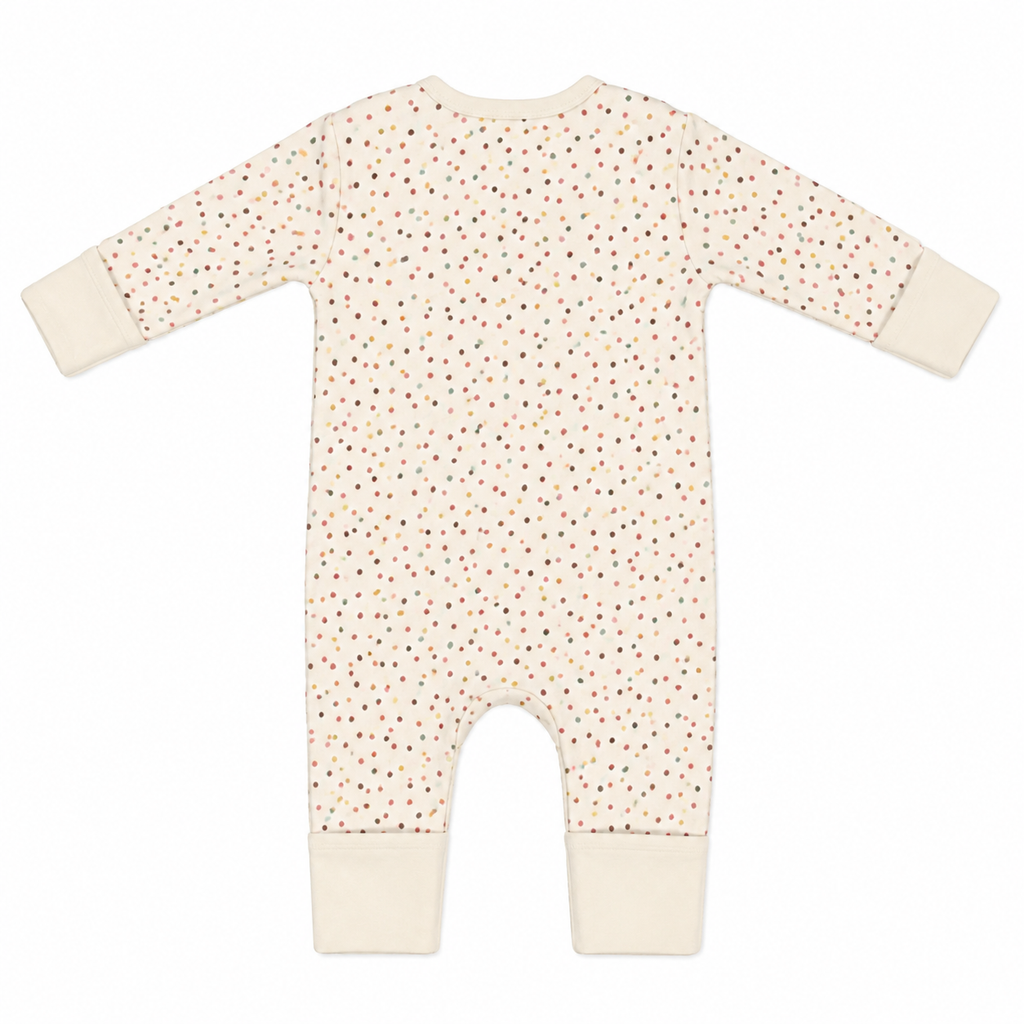 A long-sleeve baby romper in cream with a small multicolor polka dot pattern and solid cream cuffs and leg openings, shown flat on a white background.