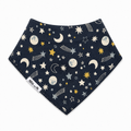 A triangular bandana bib with a dark navy blue space-themed print featuring stars, moons, and shooting stars, finished with a soft fleece border. A white fabric tag on the left side reads 'Millie and Me'.